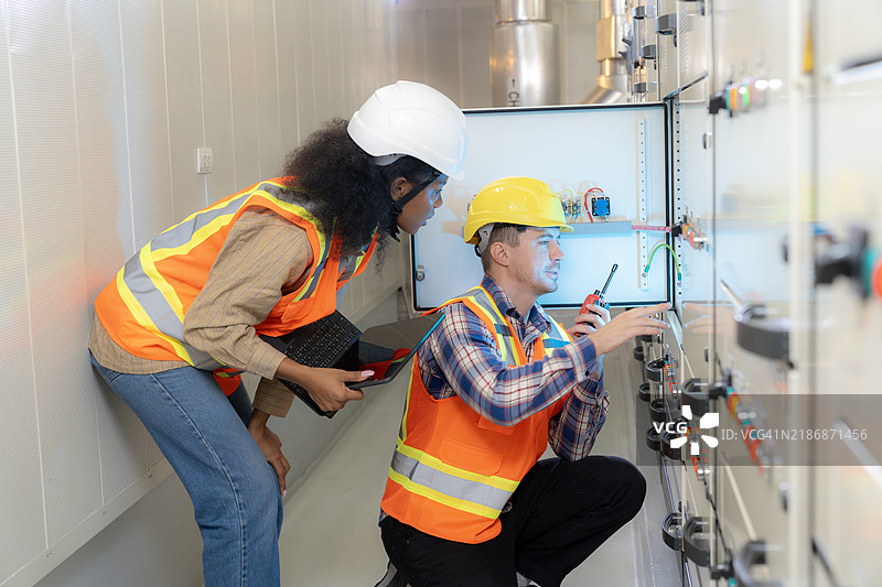 两名电气工程师正在研究一个开关柜图片素材