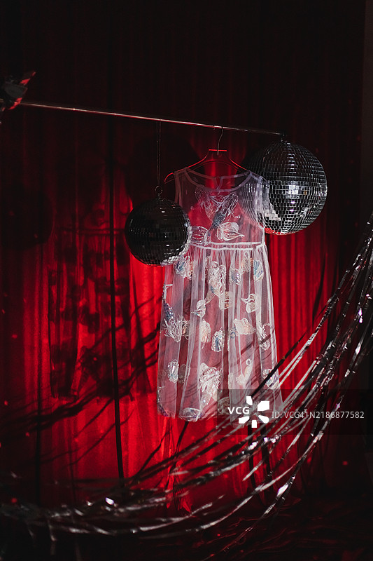 美丽的亮片裙在红色天鹅绒背景下与迪斯科球和银色闪光带相映成趣。图片素材