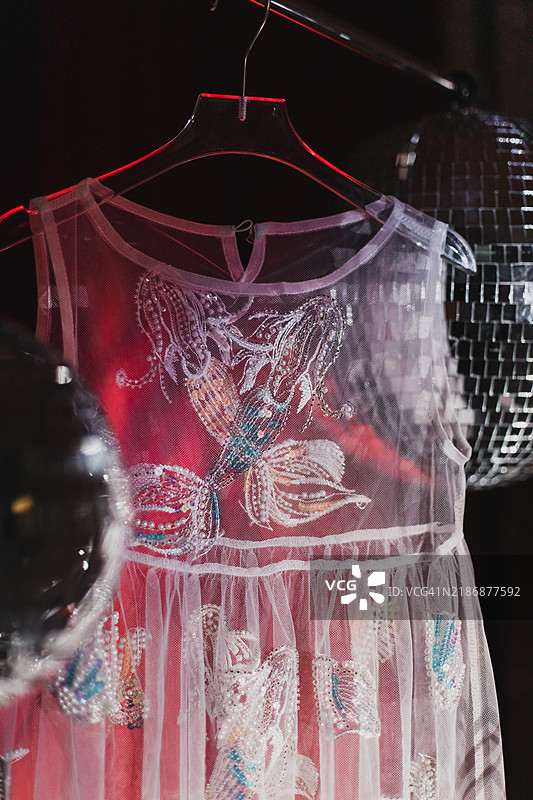 美丽的亮片裙在红色天鹅绒背景下与迪斯科球和银色闪光带相映成趣。图片素材