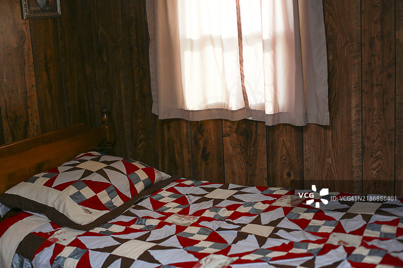 度假租赁小屋中的卧室，旧床上铺着复古被子图片素材