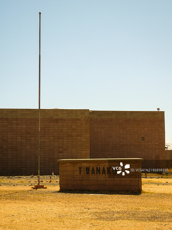 博利维亚高原的提瓦纳库遗址和博物馆入口处的标志，周围是黄色干燥的土地和晴朗的天空图片素材