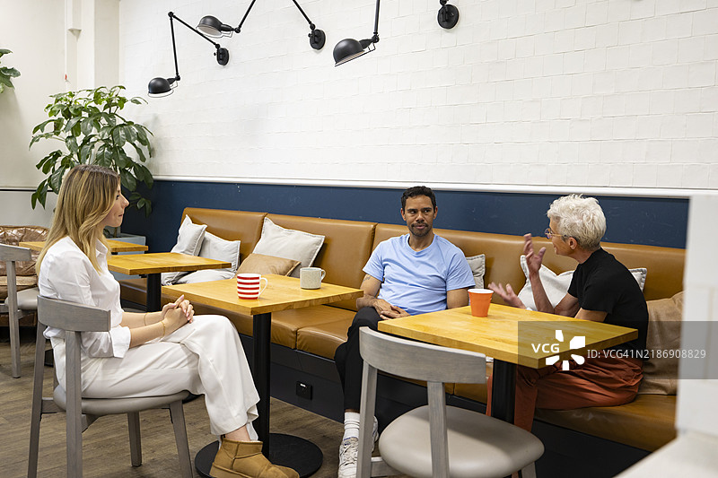 现代办公室：同事们在办公室咖啡馆讨论。图片素材