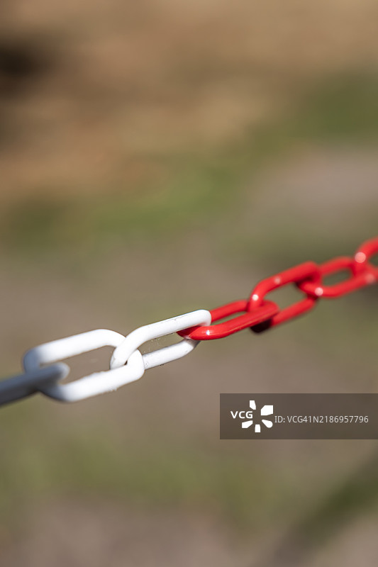红白相间的隔离链，背景是一片草地图片素材