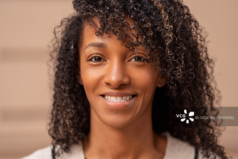 微笑的年轻黑人女性，卷发，摆姿势拍摄肖像图片素材