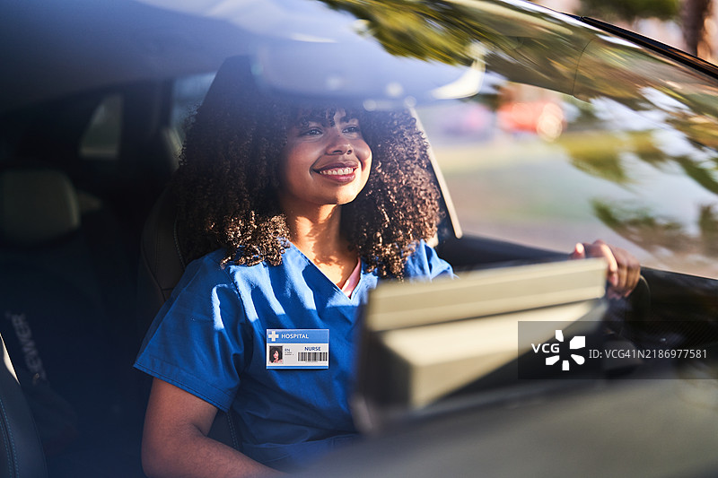 微笑的护士开车，佩戴医院身份证明牌图片素材