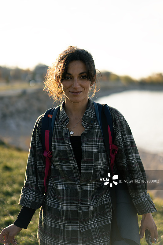 年轻女性在湖边徒步旅行，背着背包和瑜伽垫图片素材