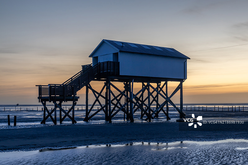 旅行目的地：圣彼得-奥尔丁海滩上的高脚屋，日落时分（德国，石勒苏益格-荷尔斯泰因）图片素材