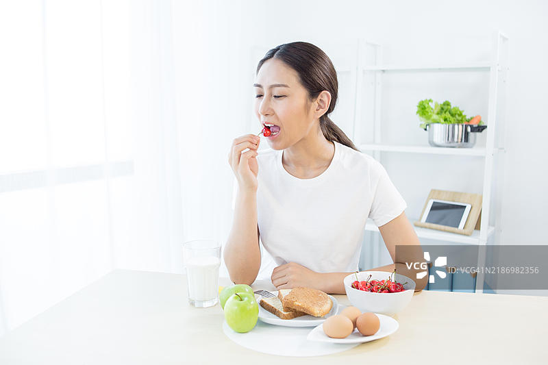 亚洲女性在厨房吃早餐图片素材