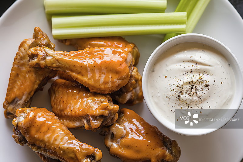 一盘上釉的鸡翅，配有新鲜的芹菜棒图片素材