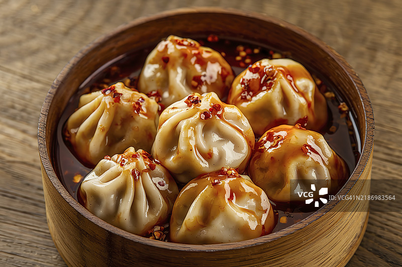 一碗装满金棕色饺子的碗，饺子表面似乎涂有光泽的酱汁。图片素材