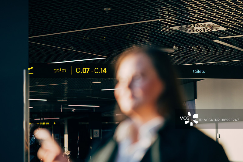 模糊的旅客在机场航站楼与登机口标志图片素材