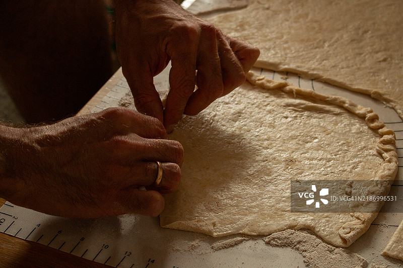 双手在撒了面粉的表面上揉面团图片素材