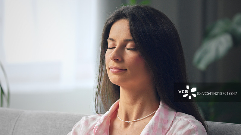 年轻女性闭眼放松在沙发上图片素材