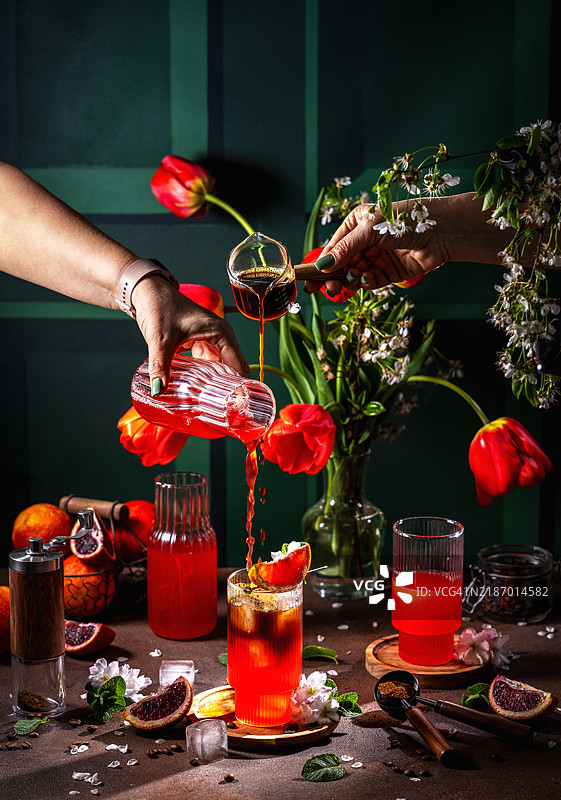 调酒师正在倒入红色鸡尾酒，配有咖啡和橙子，制作清爽的热带饮品，乌克兰图片素材