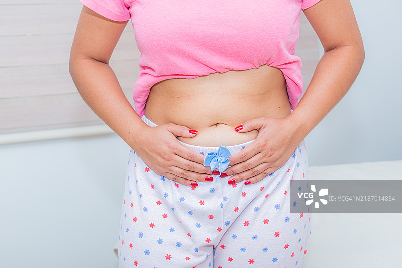 一位感到子宫疼痛的女性触摸着腹部的特写镜头图片素材