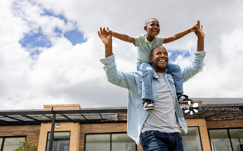 快乐的父亲在自家门外背着儿子玩耍图片素材