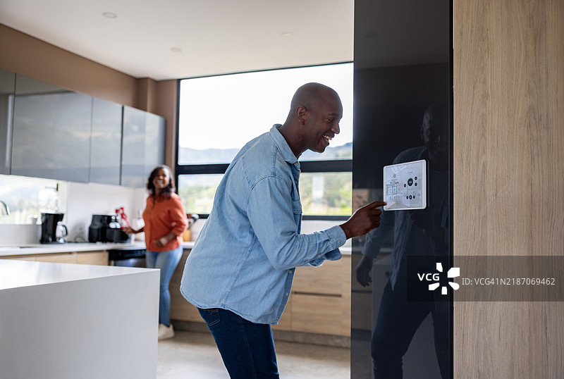 男人在家与妻子一起做饭时，通过平板电脑控制音乐图片素材