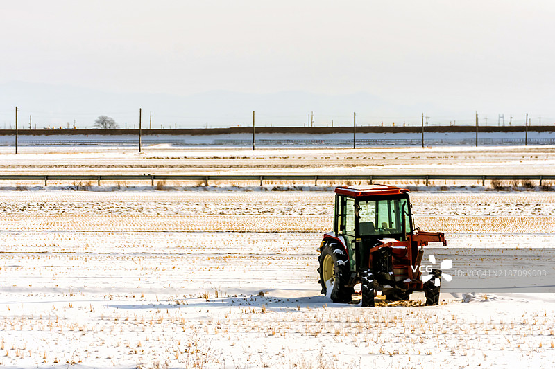 雪覆盖的田野中的红色拖拉机图片素材