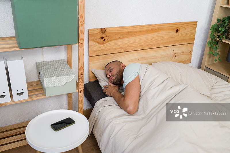 年轻男子在现代简约风格的卧室里安静地睡觉图片素材