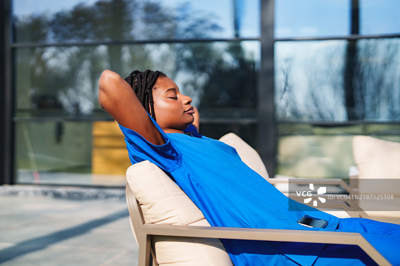 穿着蓝色护士服的非洲裔女性医疗工作者在阳光下休息。图片素材