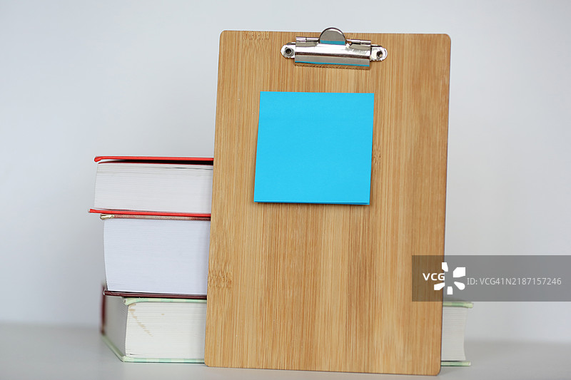 蓝色粘性贴纸放在木质桌子支架上，背景是书堆。图片素材