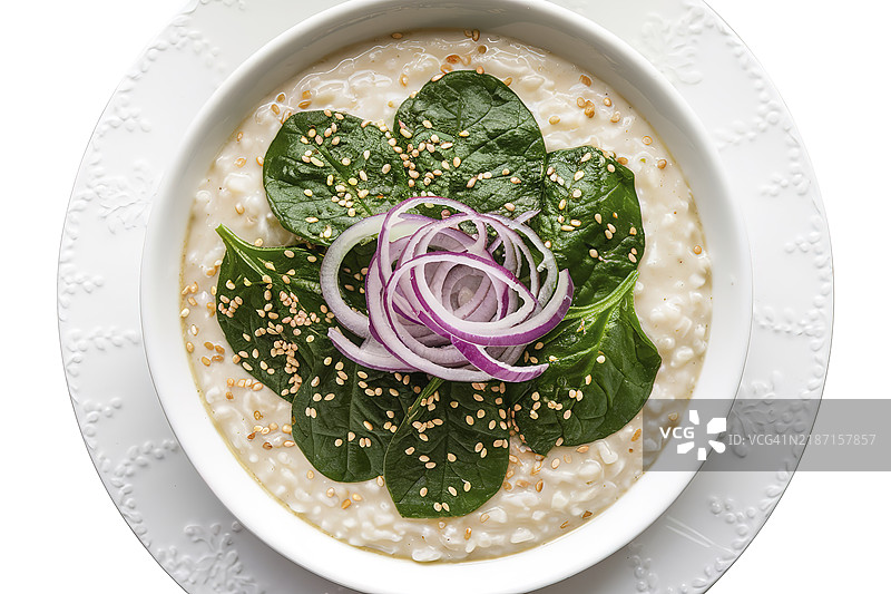 一碗奶油粥，上面放着煮熟的鲜绿色菠菜叶的中景拍摄。图片素材