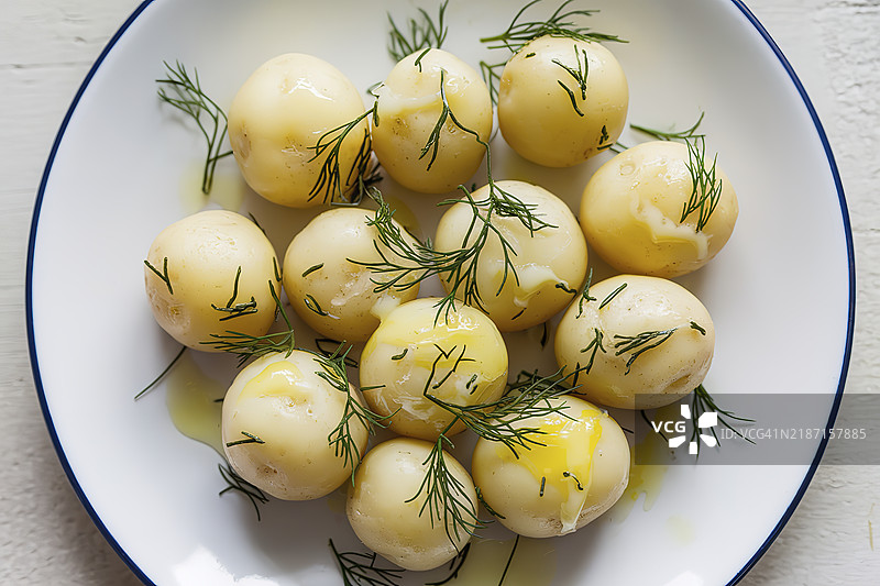 白盘上的年轻煮土豆，配有黄油和莳萝图片素材