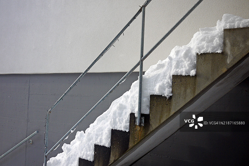 户外楼梯，覆盖着雪，金属栏杆与灰色墙壁图片素材