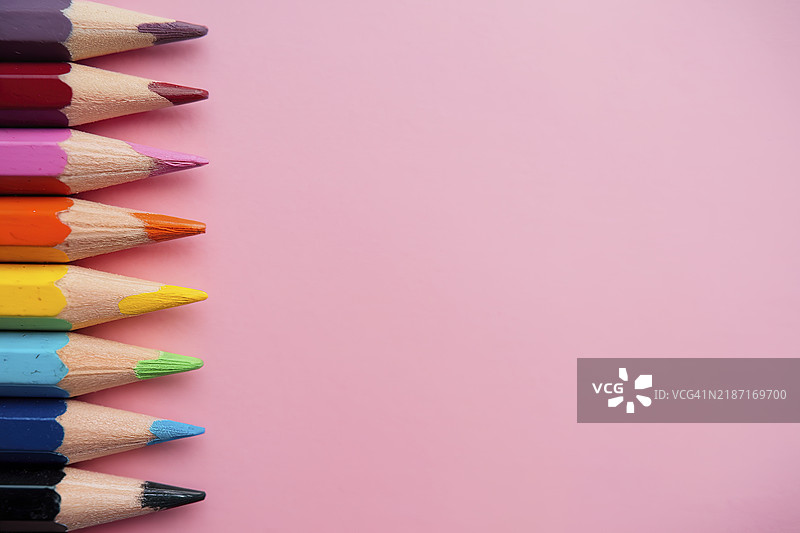 一排五颜六色的铅笔垂直排列在粉色背景上图片素材