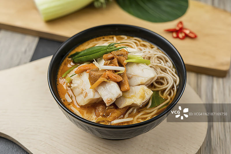 一碗鱼酸汤，里面有切块的鱼、咖喱和新鲜蔬菜。图片素材