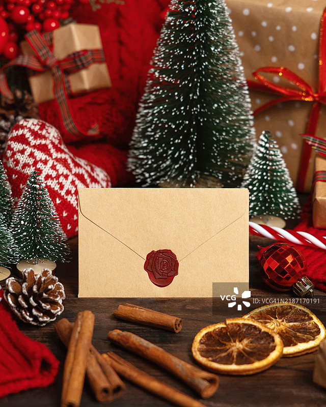 封闭的信封靠近圣诞装饰、树木、香料和红色针织毛衣，冬季样机图片素材