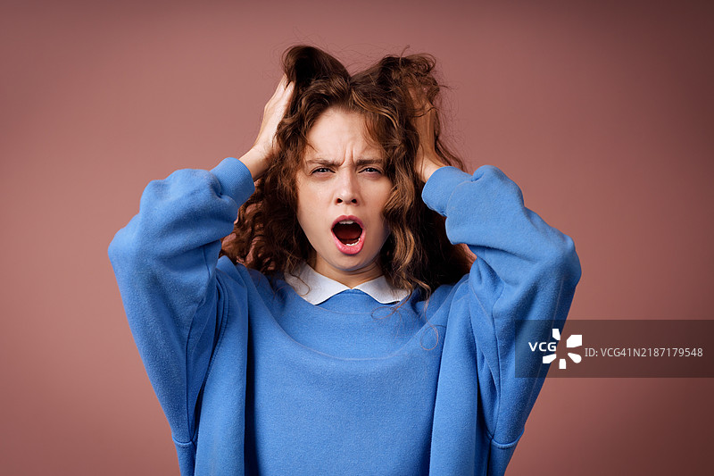 打哈欠的年轻女性肖像，显得无聊和疲惫，嘴巴张开。图片素材