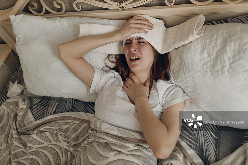 年轻女性在家中因感冒生病，头痛不适。图片素材