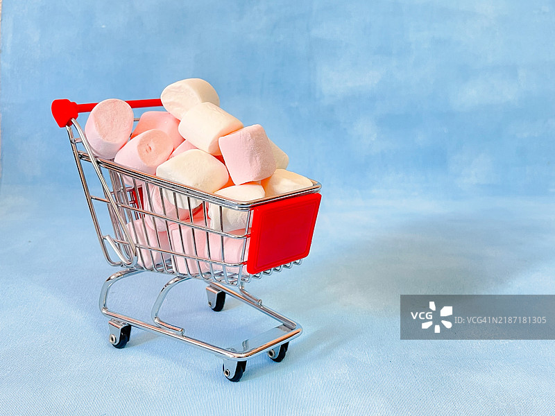 超市迷你购物车与棉花糖，蓝色背景图片素材