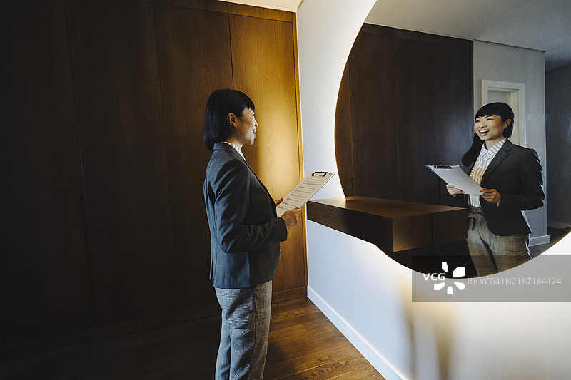 一位女性在家中对着镜子排练演讲。图片素材