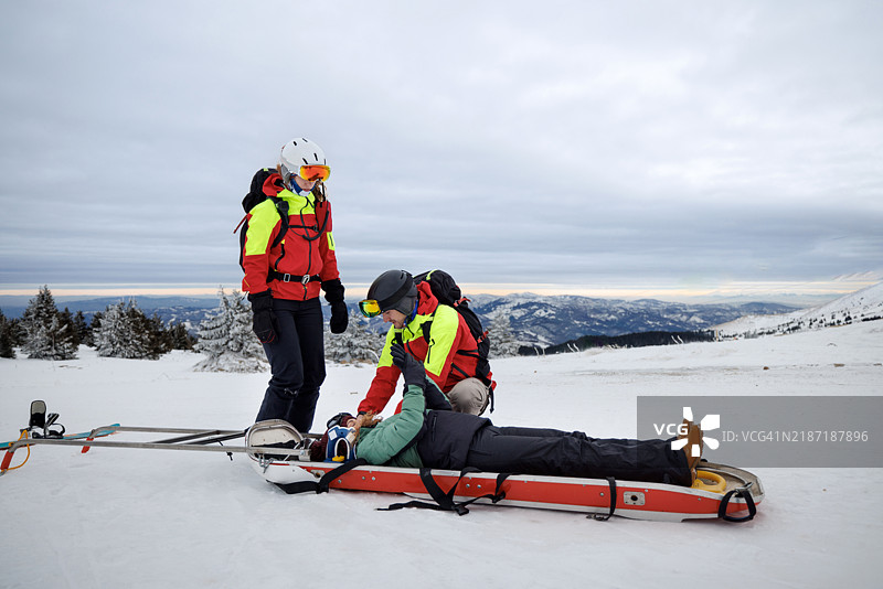 救援人员在山上协助受伤的滑雪者图片素材