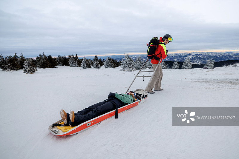 男性救援人员正在用雪橇拉伤者滑雪者图片素材