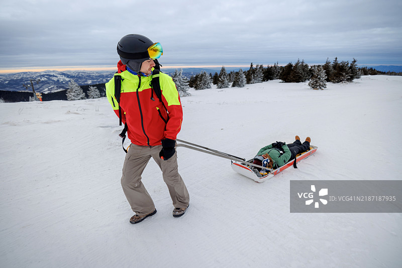 男性救援人员正在用雪橇拉伤者滑雪者图片素材