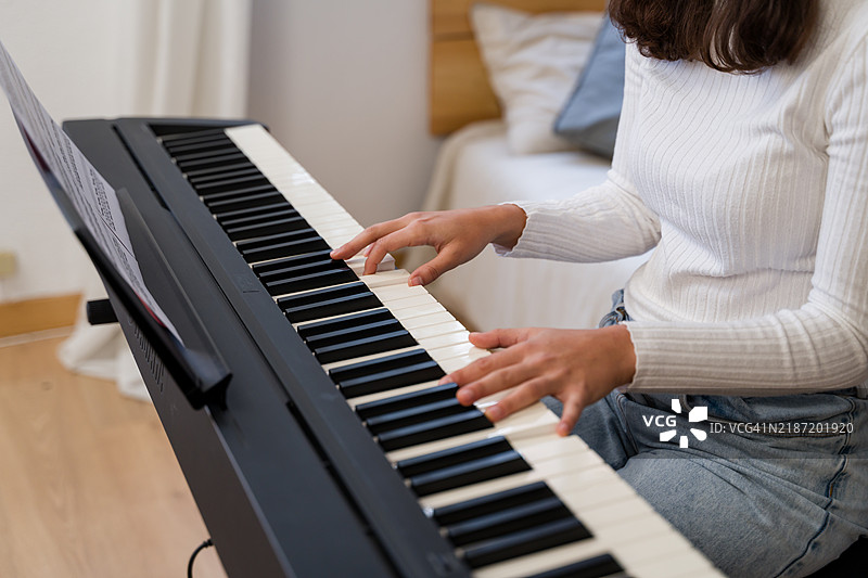 在家中跟随乐谱弹钢琴的女性图片素材