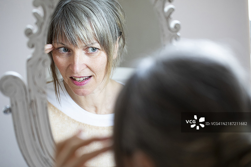 自然成熟的灰发女性自信地看着镜子图片素材
