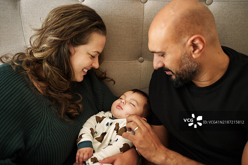 年轻父母静静地看着他们安详入睡的宝宝。图片素材