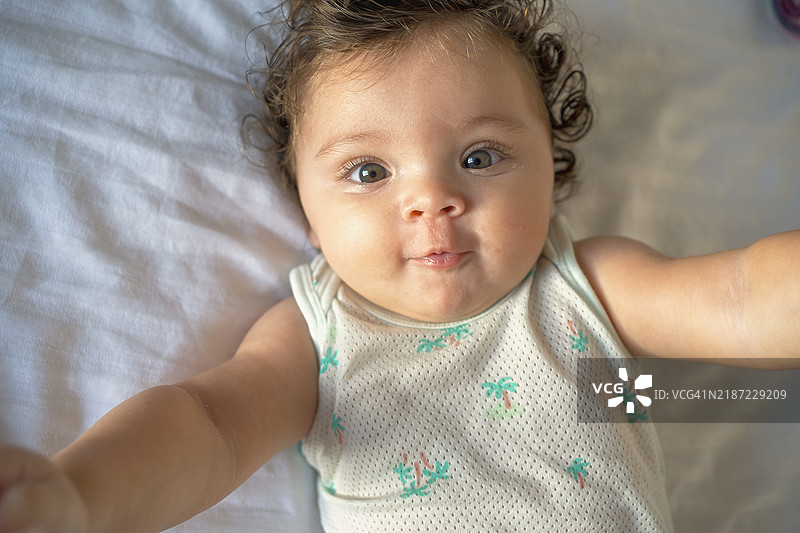 可爱宝宝在床上微笑的特写肖像图片素材
