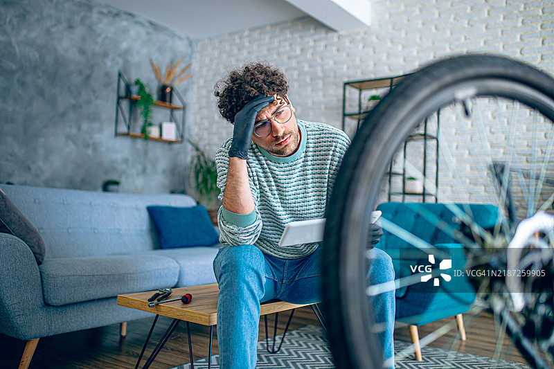 男子在家中使用平板电脑修理自行车图片素材