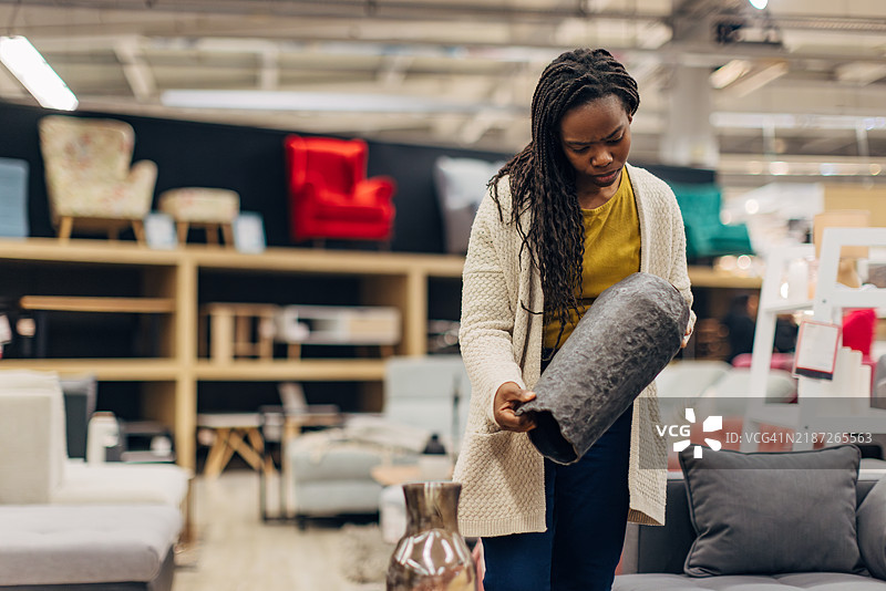 无忧无虑的黑人女性想购买客厅装饰和花瓶。她在百货商店查看花瓶的选择和价格。图片素材