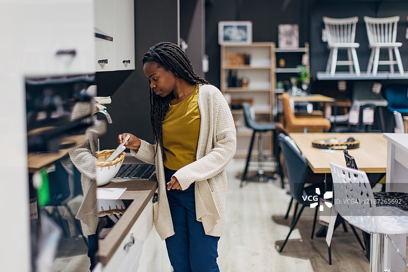 一位黑人女性正在百货商店里查看她为新公寓购买的厨房。图片素材