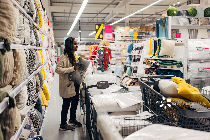一位黑人女性从百货商店的货架上拿起了一只她喜欢的枕头。在百货商店购买枕头图片素材