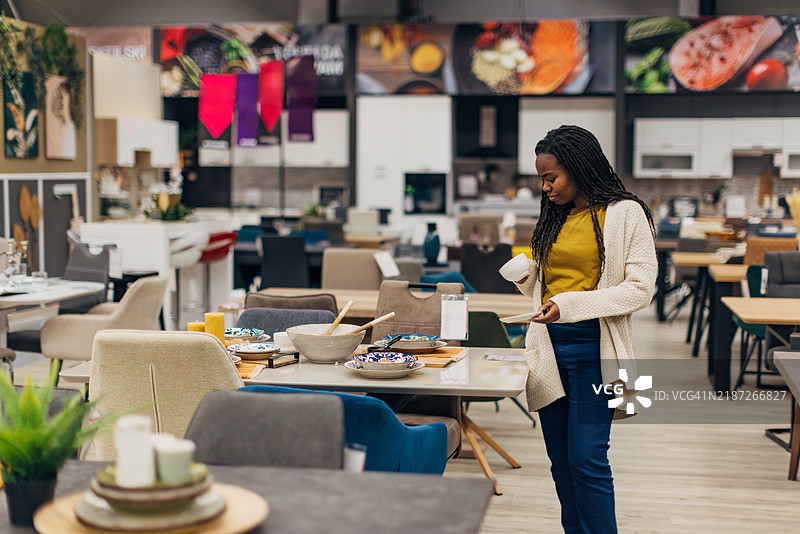 一位黑人女性在百货商店浏览，寻找适合她新家的理想餐桌和椅子。图片素材