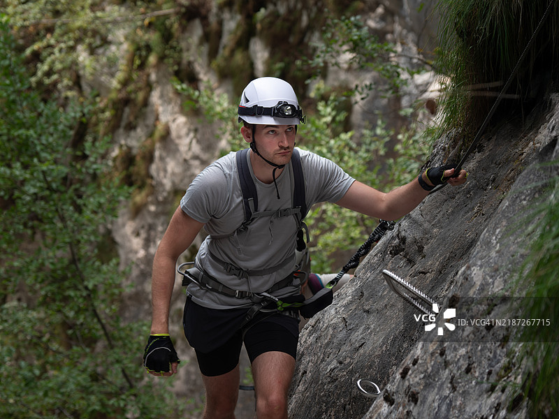 从正面看到的攀岩者在铁索路上抓住一根绳索。图片素材