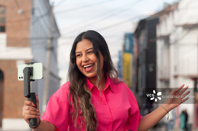 年轻女性在城市中录制视频，微笑着记录她的独自旅行冒险。世界旅游日图片素材
