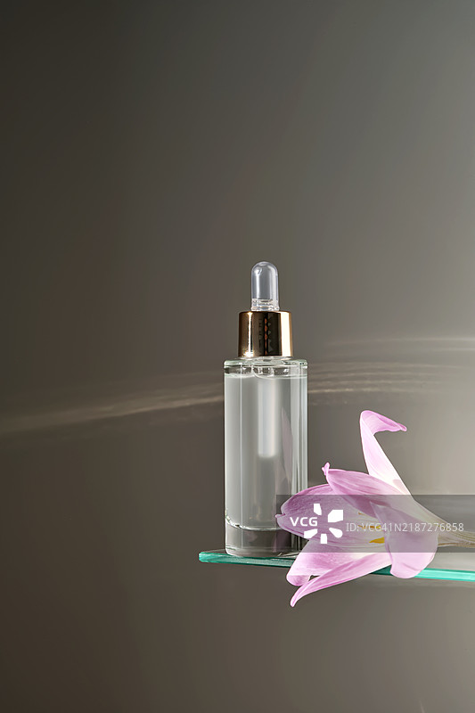 浴室玻璃架上的滴管面部精华液。图片素材